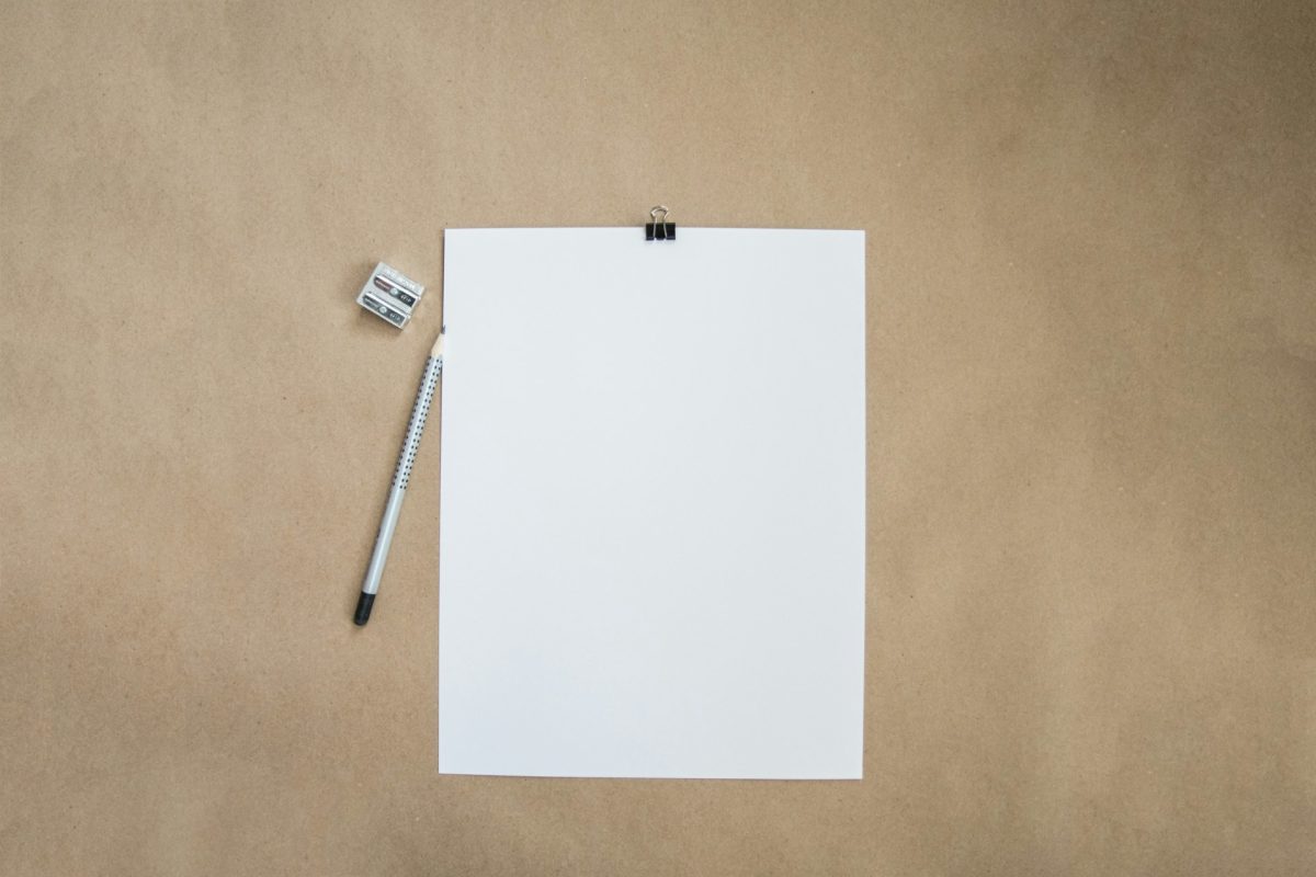 Une feuille de papier blanche, un crayon et un taille-crayon sur du papier kraft, pour illustrer les meilleures apps de notes en 2026