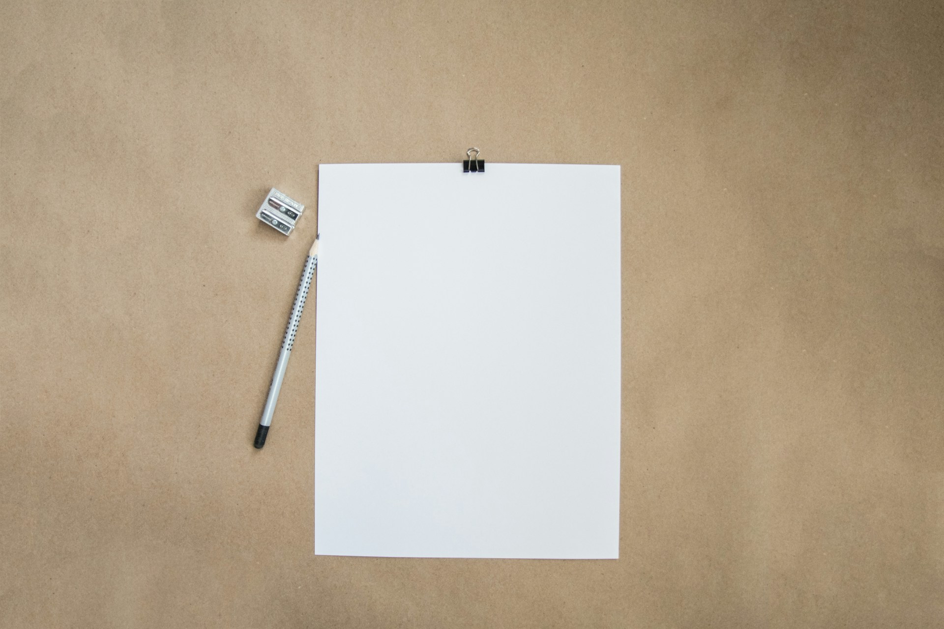 Une feuille de papier blanche, un crayon et un taille-crayon sur du papier kraft, pour illustrer les meilleures apps de notes en 2026